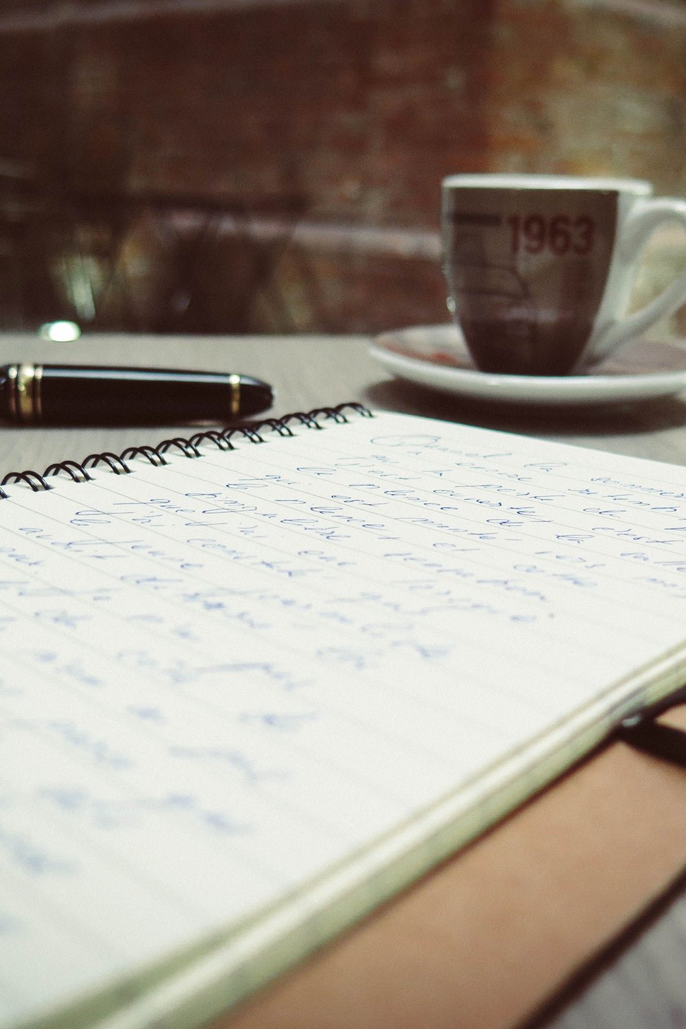 Notizblock mit Handschrift, Füllfeder und Kaffeetasse auf einem Tisch