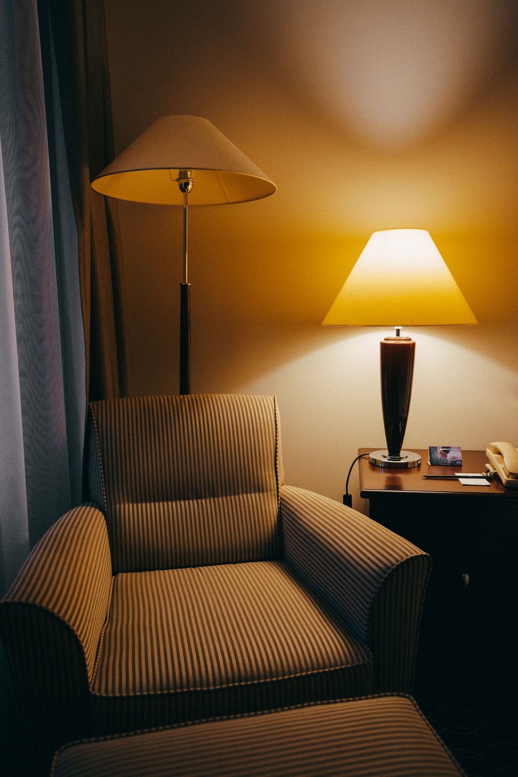 Gestreifter Sessel neben einer warm leuchtenden Lampe am Abend